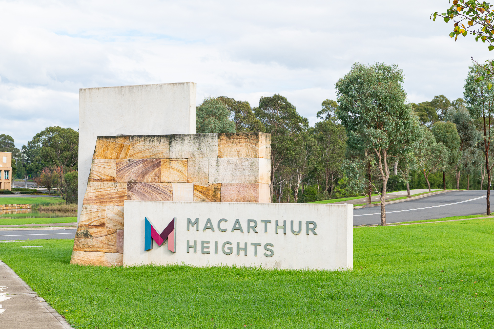 The Macarthur Heights sandstone entry sign surrounded by lawn and gum trees