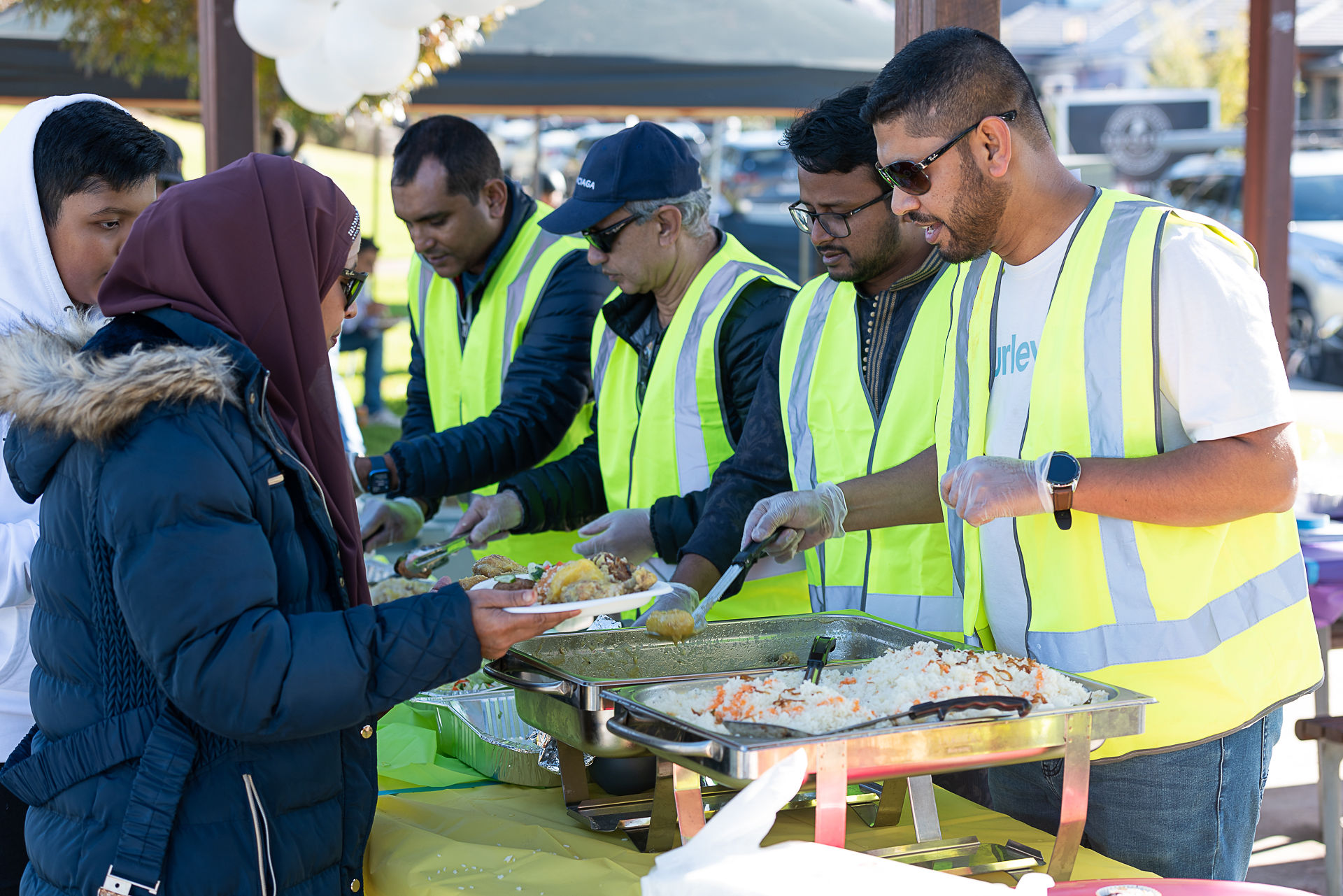 MHCG volunteers serving food to neighbours at a community barbecue